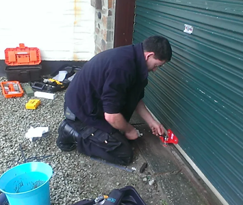 Locksmith repairing a broken garage door lock